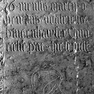 Grabinschrift für den Kanoniker Ulrich Hinzenhauser auf der Grabplatte für den Kanoniker Ruger (Nr. 28), an der Nordwand. Zweitverwendung der Platte. Inschrift fünf Zeilen im oberen Drittel der Platte, Beschriftung zur ursprünglichen Ausrichtung der Platt