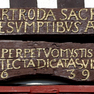Farbiger Türsturz mit Gold auf Braun gefasster Inschrift zwischen Wappenschilden
