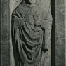Grabplatte eines Klerikers aus rotem Marmor, an der Wand aufgerichtet.