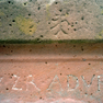Initialen und Steinmetzzeichen auf der vorderen Längsseite eines Brunnentroges.