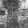 Grabinschrift auf einem Grabkreuz, das heute in der Einfriedungsmauer des Pfarrgartens eingemauert ist.