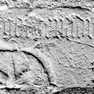 Zwei Fragmente des unteren Teils einer Grabplatte, außen an der Südwand des Chors im Pfarrgarten, als Mauersteine behauen und verwendet. Granit.